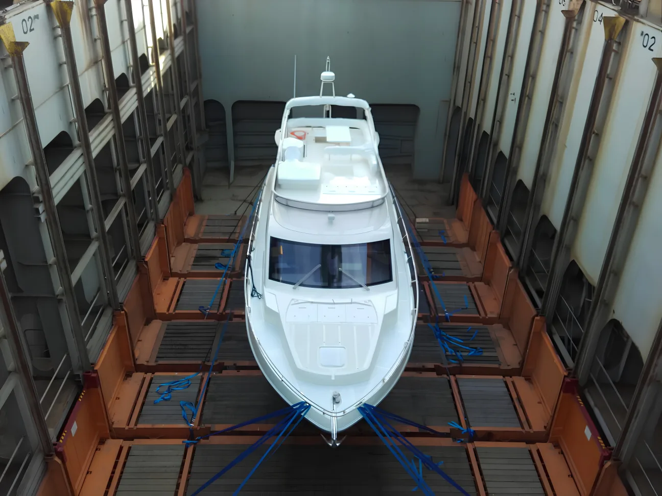 Superyacht being crane-lifted onto cargo vessel for transport to Australia
